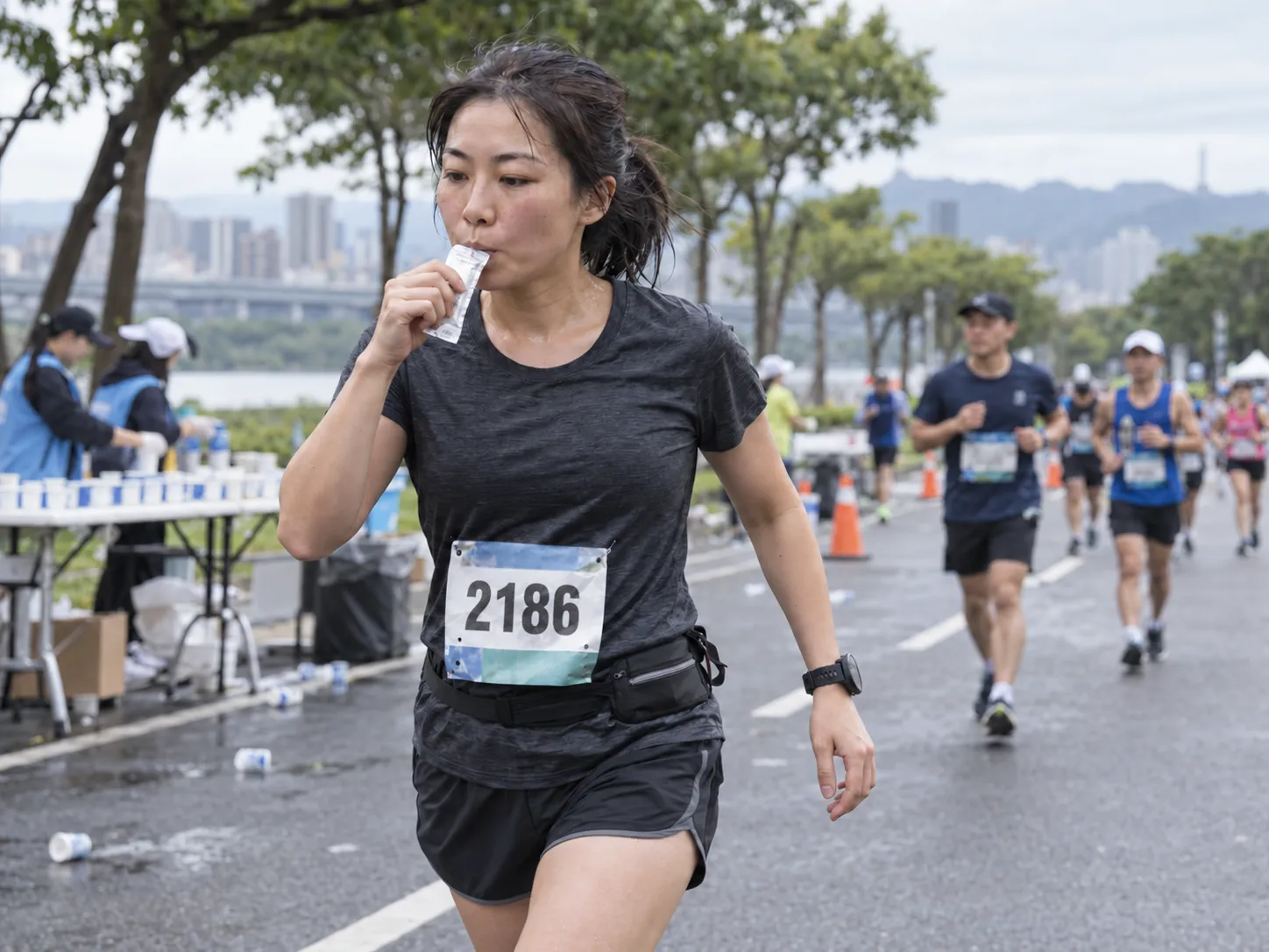 半馬跑者在賽道補給站附近放慢速度，手持能量膠準備搭配開水補充碳水化合物